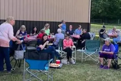 A group of people sitting in lawn chairs outside.