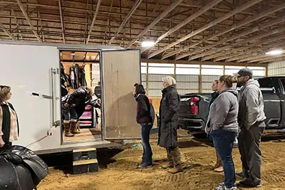 A group of people standing around in front of a truck.